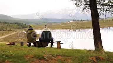 两个成年人的后景，坐在长凳上，花时间环顾<strong>山湖美景</strong>